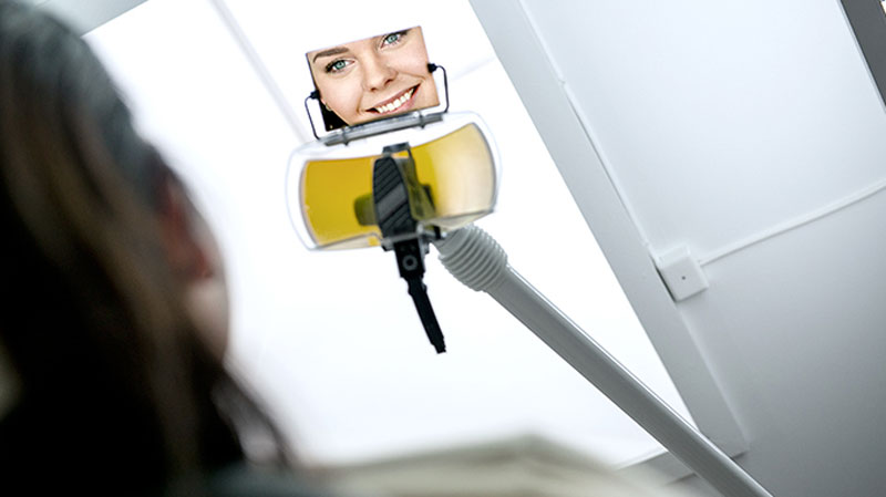 Patient som tittar i tandläkarspegel